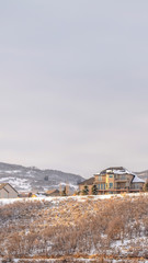 Photo Vertical frame Houses on residential area nestled on hills blanketed with snow in winter