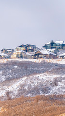 Photo Vertical frame Hill scenery with homes built on top of snow covered slopes against cloudy sky