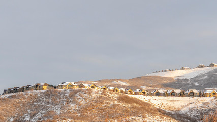 Panorama Sunlight beaming down on snow covered hills with houses built on gentle slopes