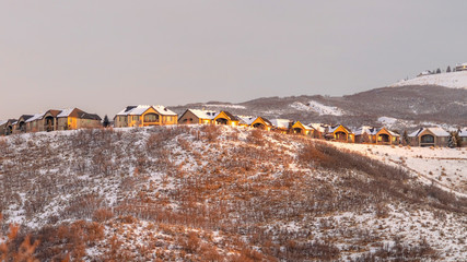 Photo Panorama Neighborhood homes on top of snowy hills against cloudy sky at sunset