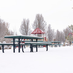 Square frame Thick layer of fresh white snow covering a park with playground and picnic area