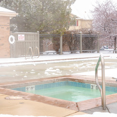 Square Frozen swimming pool area surrounded by snow on a foggy and cold winter day