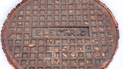 Photo Panorama frame Rusty circular utility electric manhole cover amid fresh white snow in winter