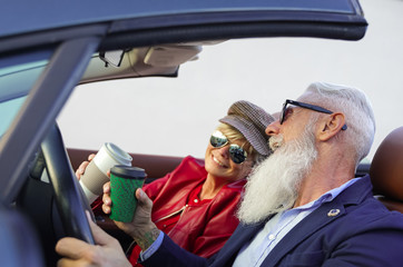 Couple drinking a coffee in a cabriolet car. Retired people happy for fantastic holiday. Road trip,...