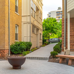 Square frame Fire pit on circular patio outside building with white and stone brick wall