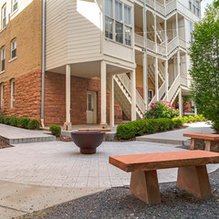 Square Fire pit and stone benches against building with stone brick wall and staircases