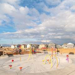 Fototapeta premium Square frame Colorful childrens playground against houses and overcast blue sky in winter