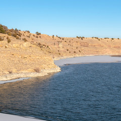 Square frame Scenic lake view with frozen water near the base of a rocky slope terrain