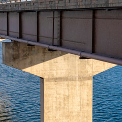 Square frame Deck of a beam bridge supported by abutments or piers spanning over blue water