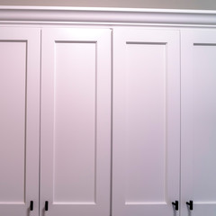 Square White wooden cabinets with black handles mounted on the wall of a home