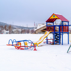 Square Colorful playground with slides swings seesaws and climbers against snow