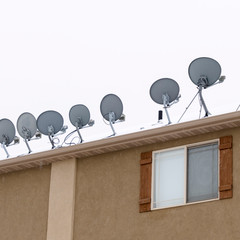 Square frame Bowl shaped antennas mounted on the snowy roof of residential building in winter