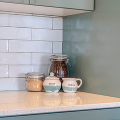 Obraz na płótnie Canvas Photo Square frame Jars of coffee beans sugar and cream on a countertop with tile backsplash