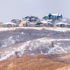 Square Hill scenery with homes built on top of snow covered slopes against cloudy sky