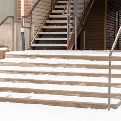 Square frame Building entrance with snow covering the stairs and yard during winter season