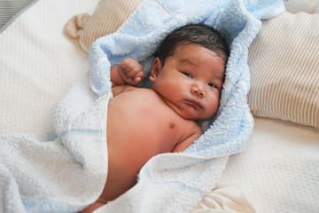 A baby is ready for taking a shower. Baby is covered by towel.