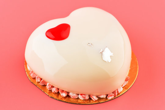Cake. One small mousse  white cake  in heart shape  on a pink background. Vertical photo