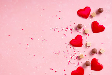 Red fabric hearts, sugar cubes, confetti, sweets candy chocolate on pink background. Valentines day 14 february love minimal concept. Flat lay, copy space, space for text, banner