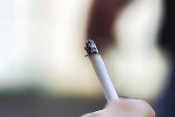 Young man's hand holding a cigarette with smoke
