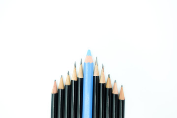 Top view of a group of sharp black pencils and blue pencil in the middle, arranged in a triangle corner isolated on white background with copy space. For leadership, teamwork and goal setting theme