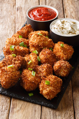 Crispy coconut chicken nuggets served with ketchup and mayonnaise close-up on a table. Vertical