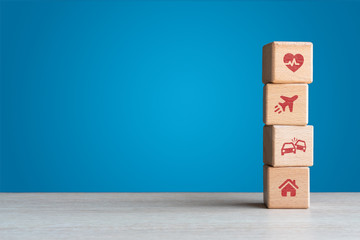 Travel medical car and home insurance icons on wood blocks concept with blue backdrop 