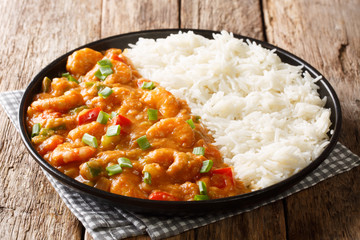 Serving of shrimp Etouffee with vegetables and sauce served with rice closeup in a plate. horizontal