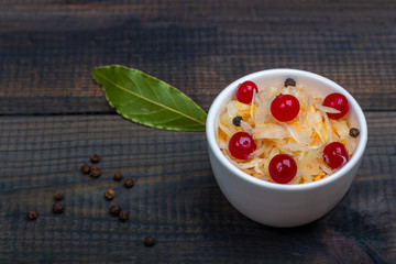 Sauerkraut or fermented cabbage with cranberries in a bowl on rustic wooden background. The concept of proper nutrition and healthy eating. Organic and vegetarian food. Close up, copy space for text
