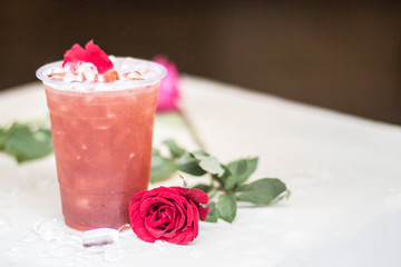 Natural flower The red rose is on the white table and there is a rose drink in the background. Giving a feeling of love.