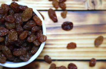 Brown raisins in a white plate on a wooden table