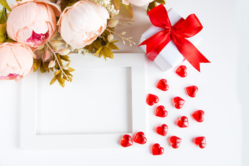 Holiday card for Valentine's Day. White frame, red glass hearts, a bouquet of pink flowers, a gift...