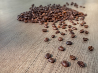Black coffee in grains on the surface of a wooden table.