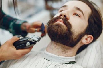 Man with a beard. Hairdresser with a client. Woman with a comb and shaving machine