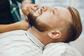 Man with a beard. Hairdresser with a client. Woman with a comb and scissors