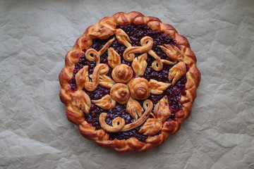Delicious golden round pie with red cherry and lingonberry filling with dough pattern