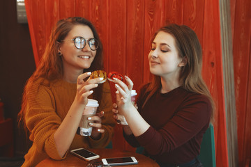 very cute smiling women drinking a coffee sitting inside in a cafe bistro