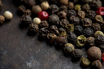 Mixed peppercorns on the rustic background. Selective focus. Shallow depth of field.