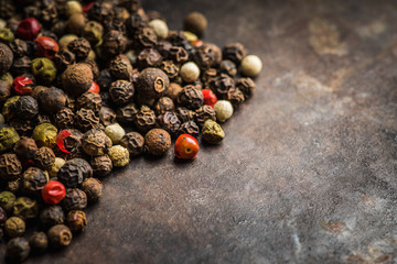 Mixed peppercorns on the rustic background. Selective focus. Shallow depth of field.