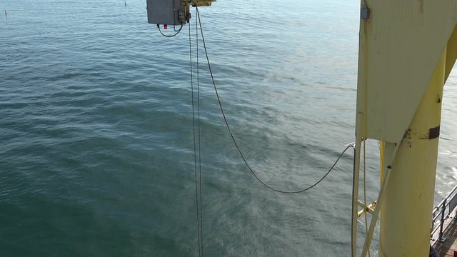 Close up of a boat hoist on a dock with the ocean below