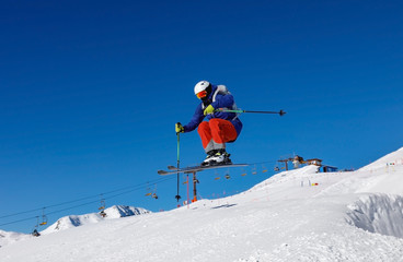 Skier jumps in snow park against the blue sky in Livigno ski resort, Italy