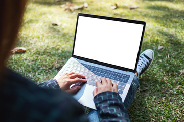 Mockup image of a woman using and typing on laptop with blank white screen , sitting in the...