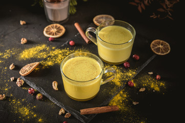 Golden turmeric latte with spices on dark background