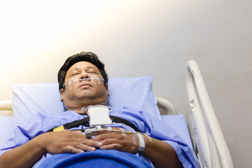 Asian Man Sleeping On A Patient Bed With Breathing Equipment in Hospital.