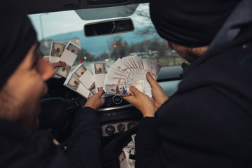 Two happy bank robbers celebrating their successful hit while sitting in the car they used for the...