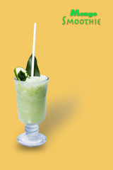 Mango smoothie in a tall glass. Drink in summer on a yellow background.