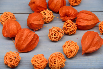 Bright orange physalis and wicker balls on a blue wooden background.