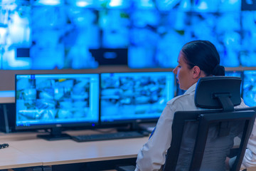 Group of Security data center operators (administrators) working in a group at a CCTV monitoring room while looking at multiple monitors ( computer screens)