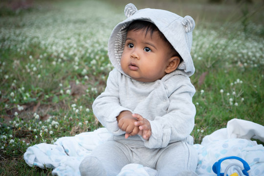 Cute little asina baby sitting at white flower garden