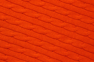 Abstract bright orange knitted background. Yarn pattern, jersey surface, knitwear wallpaper. Ornament of acrylic braids. Woolen weave.