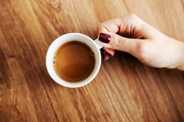 Top view of woman taking fresh morning coffee arabica from a table.